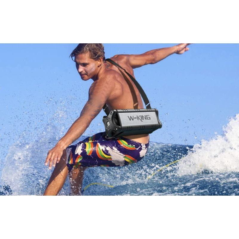 Jeune homme avec l'Enceinte W-KING D8 Noir suspendue pendant qu'il surfe